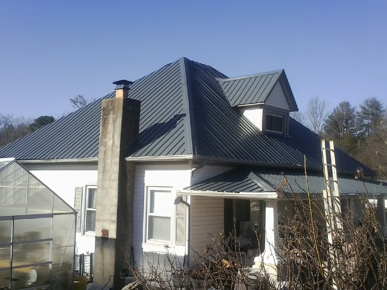 Dark blue standing seam metal roof on a white farmhouse with dormer — Slate & Tile Roof Repair by Roofing Brothers in Tabiona