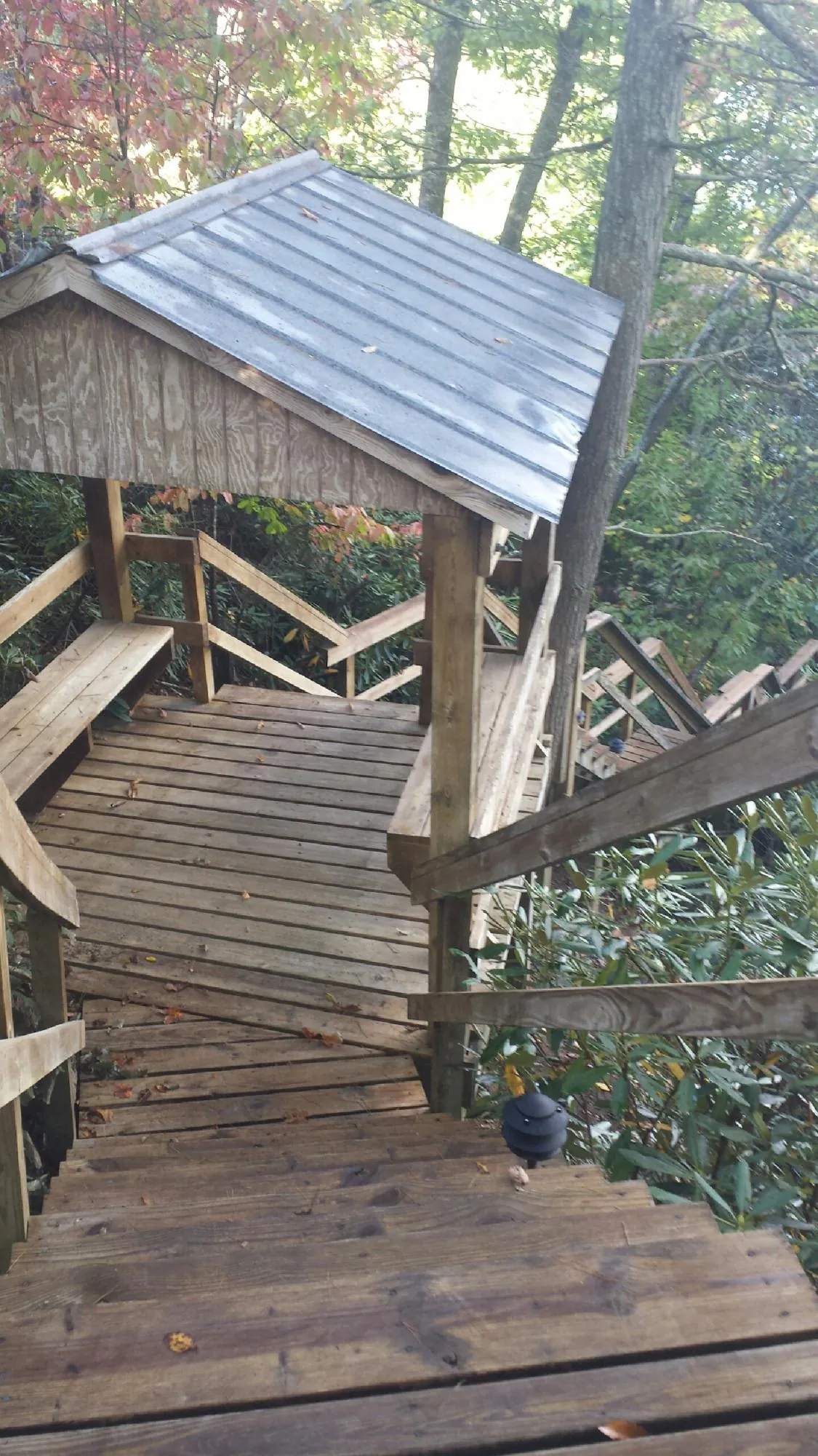 Metal roofed shelter over wooden steps on a wooded walkway — Skylight Repair & Installation work by our crew in Tabiona